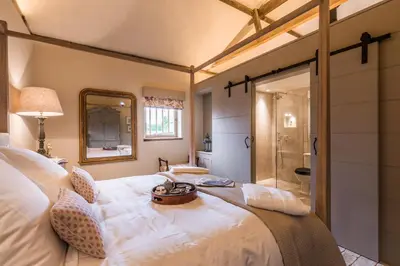 a bedroom with a large white bed and a shower at Cambridge Country Cottages in Cambridge