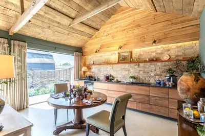 a kitchen with a wooden ceiling and a table and chairs at Cambridge Country Cottages in Cambridge