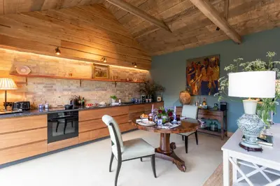 a kitchen with wooden walls and a table and chairs at Cambridge Country Cottages in Cambridge