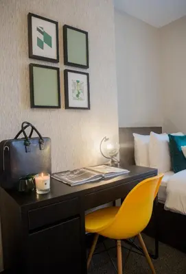a desk in a hotel room with a yellow chair and a bed at Wherstead House in Ipswich
