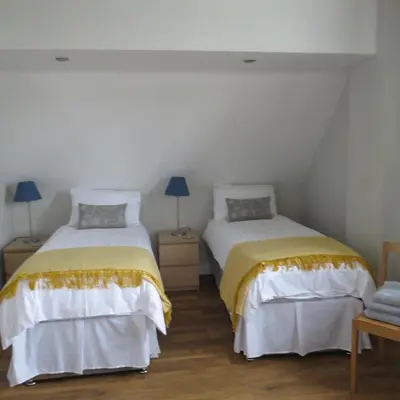 a room with two beds and a table with a chair at Maltings Loft in Hepworth