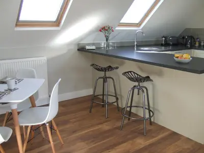 a kitchen with a counter and a table and stools at Maltings Loft in Hepworth