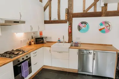 a kitchen with white cabinets and a sink at Creeksea Place Barns in Burnham on Crouch