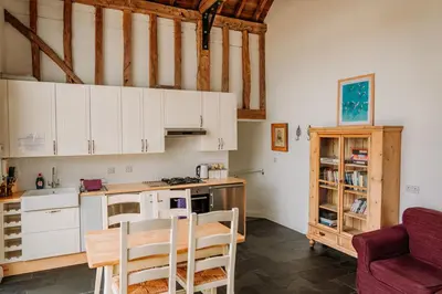 a kitchen with white cabinets and a table and chairs at Creeksea Place Barns in Burnham on Crouch