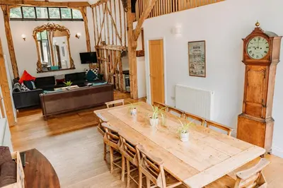 a dining room with a table and a grandfather clock at Creeksea Place Barns in Burnham on Crouch