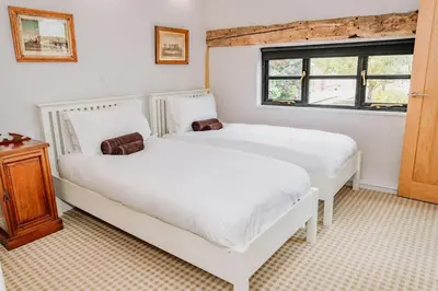 two white beds in a room with a window at Creeksea Place Barns in Burnham on Crouch