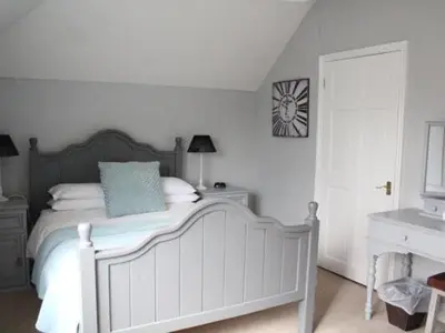 a bedroom with a bed and a clock on the wall at Frasers in Battlesbridge