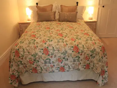 a large bed with a floral bedspread on it at Church Farmhouse B & B in Kennett
