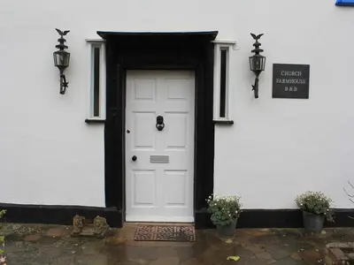 a white house with a white door and a sign at Church Farmhouse B & B in Kennett