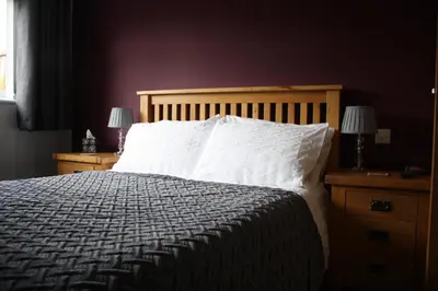 a bedroom with a bed and two night stands with lamps at Amberleigh House Annex in Newmarket