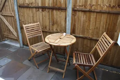 two chairs and a wooden table and chairs on a patio at Amberleigh House Annex in Newmarket