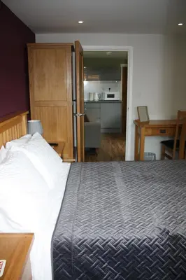 a bedroom with a large bed and a kitchen at Amberleigh House Annex in Newmarket
