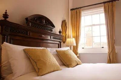 a bed with a wooden headboard and a window at Chantry Hotel in Bury Saint Edmunds