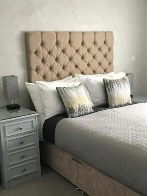 a bed with a large headboard and a night stand at The Old School House Rooms in Waterbeach