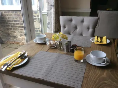 a wooden table with a breakfast of coffee and orange juice at The Old School House Rooms in Waterbeach
