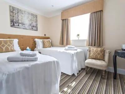 a hotel room with two beds and a chair at The Rose and Crown in Thorpe le Soken