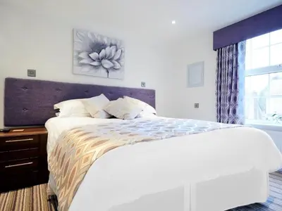 a white bedroom with a large bed and a window at The Rose and Crown in Thorpe le Soken