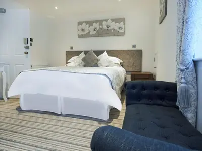 a bedroom with a large white bed and a couch at The Rose and Crown in Thorpe le Soken