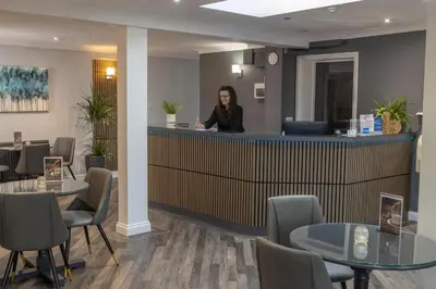a woman standing at a counter in a waiting room at Best Western Claydon Hotel in Ipswich