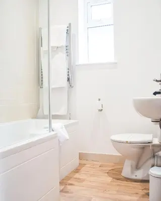 a white bathroom with a toilet and a sink at County Hotel in Chelmsford