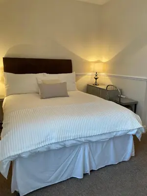 a bedroom with a large bed with a wooden headboard at CARIS Guest House in Southend-on-Sea