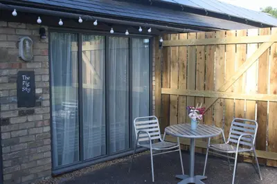a patio with a table and chairs in front of a building at Crafts Hill Barn in Cambridge