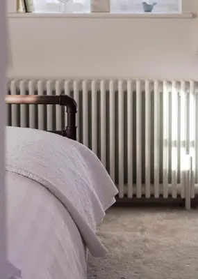 a radiator sitting in a bedroom next to a bed at Crafts Hill Barn in Cambridge