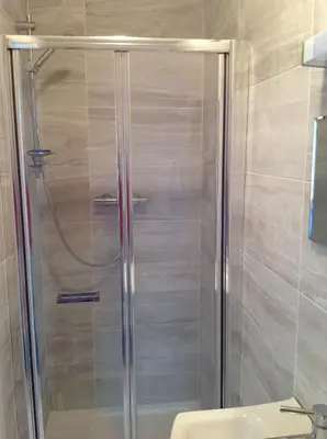 a shower with a glass door in a bathroom at Repton Private Hotel in Romford