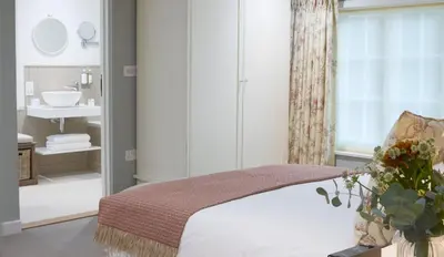 a bedroom with a bed and a bathroom with a sink at The Three Hills in Bartlow