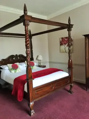 a bedroom with a four poster bed with a red blanket at Old Bull Inn in Royston