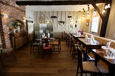 a dining room with tables and chairs and a brick wall at Old Bull Inn in Royston