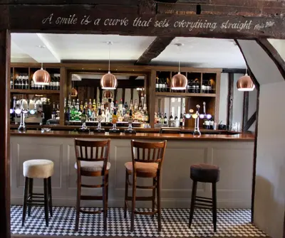 a bar with four chairs and a counter with liquor bottles at Old Bull Inn in Royston