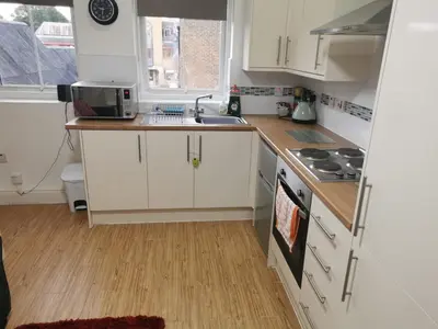 a small kitchen with white cabinets and a sink at Old Bull Inn in Royston
