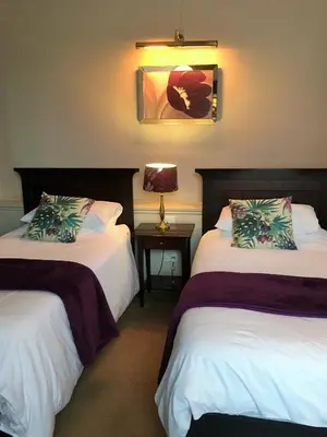 a hotel room with two beds and a table with a lamp at Old Bull Inn in Royston