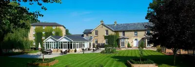 a large house with a lawn in front of it at Cambridge Quy Mill Hotel & Spa in Cambridge