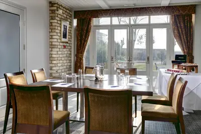 a dining room with a table and chairs and a window at Cambridge Quy Mill Hotel & Spa in Cambridge