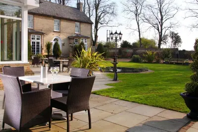 a patio with a table and chairs in a yard at Cambridge Quy Mill Hotel & Spa in Cambridge