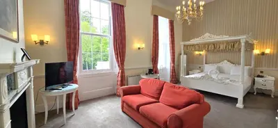 a living room with a red chair and a bed at Manor Of Groves Hotel, Golf & Health Club in Sawbridgeworth