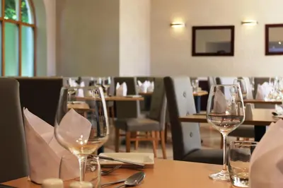 a dining room with wine glasses on a table at Manor Of Groves Hotel, Golf & Health Club in Sawbridgeworth