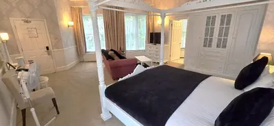 a bedroom with a bed and a living room at Manor Of Groves Hotel, Golf & Health Club in Sawbridgeworth