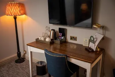 a desk in a hotel room with a television on a wall at Green Man by Chef & Brewer Collection in Harlow
