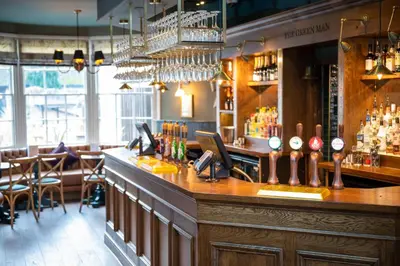 a bar in a restaurant with a counter and chairs at Green Man by Chef & Brewer Collection in Harlow