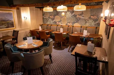a restaurant with wooden tables and chairs in a room at Green Man by Chef & Brewer Collection in Harlow