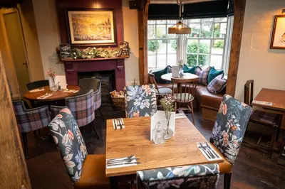 a restaurant with a wooden table and chairs and a fireplace at Green Man by Chef & Brewer Collection in Harlow
