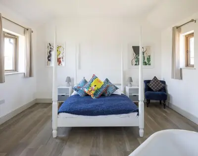 a bedroom with a white bed with a blue blanket at Clopton Courtyard Cambridge in Cambridge