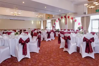 a banquet hall with white tables and red bows at Holiday Inn Ipswich Orwell by IHG in Ipswich