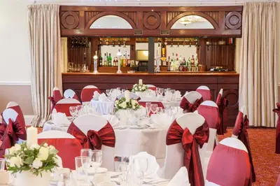 a banquet room with white tables with red bows at Holiday Inn Ipswich Orwell by IHG in Ipswich