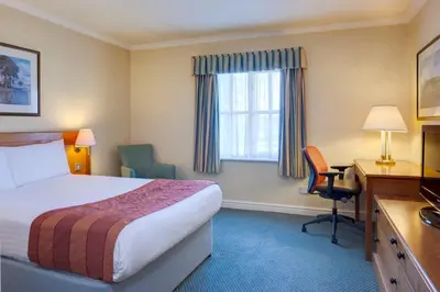 a hotel room with a bed and a desk and a window at Holiday Inn Ipswich Orwell by IHG in Ipswich