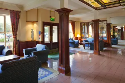 a lobby with couches and chairs in a building at Holiday Inn Ipswich Orwell by IHG in Ipswich