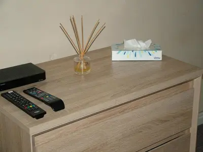 a table with two remote controls and a box on it at Thistle Cottage in Mildenhall